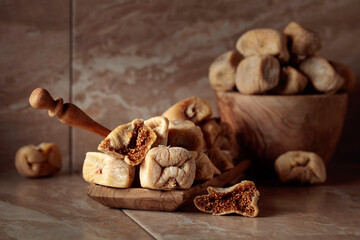 Sweet dried figs in a wooden dish on a kitchen table.