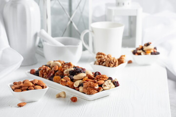 Mix of nuts and raisins on a white wooden table.