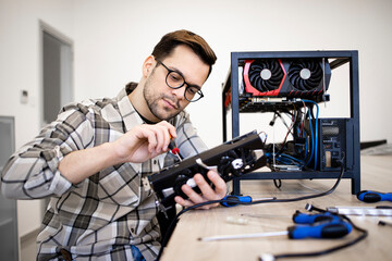 Bitcoin miner expert assembling new cryptocurrency rig and checking graphics card for mining.