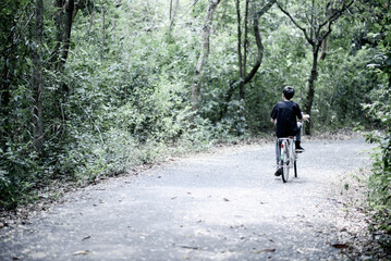 Obraz premium Teenager boy riding bicycle in the park with happy family