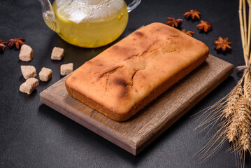 Baked rectangular cupcake with raisins and chocolate on a dark concrete background