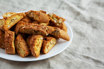 Homemade Italian Cantuccini with Almonds on a White Plate, side view. Crispy Almond Cookies. Space for text.