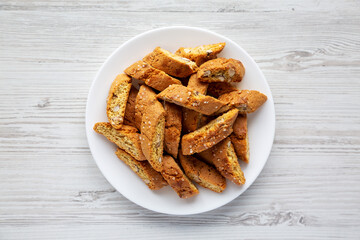 Homemade Italian Cantuccini with Almonds on a Plate on a white wooden background, top view. Crispy Almond Cookies. Flat lay, overhead, from above.