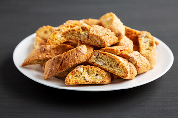 Homemade Italian Cantuccini with Almonds on a Plate on a black background, side view. Crispy Almond Cookies. Close-up.