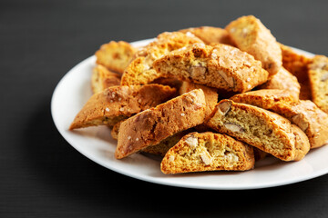 Homemade Italian Cantuccini with Almonds on a Plate on a black background, side view. Crispy Almond Cookies. Close-up.