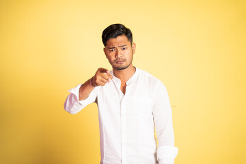 angry asian young man with finger pointing at camera on isolated background