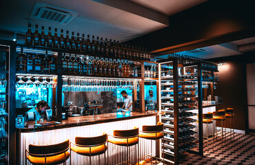 Interior of cozy luxury restaurant with original design and bottles of wine on the shelves