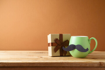 Happy Fathers day concept with green coffee cup, mustache and gift box on wooden table