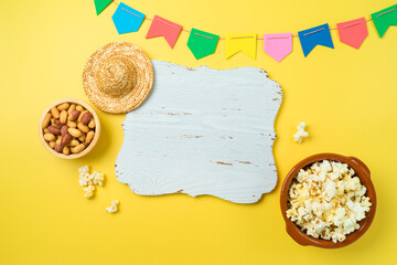 Festa Junina party background with popcorn, peanuts and wooden board. Brazilian summer harvest...