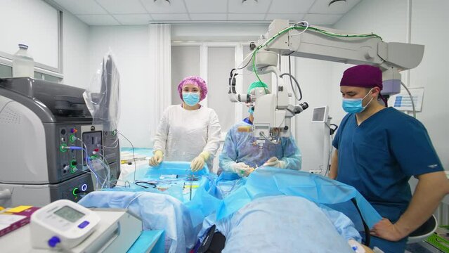 Cataract Operation In Modern Ophthalmic Clinics. Two Male Surgeons And Female Nurse Conducting Eyesight Surgery.