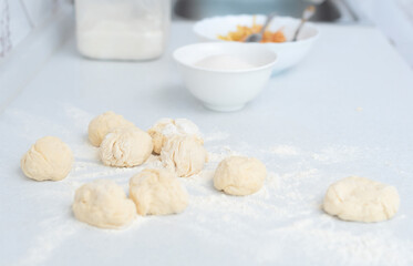 Dough and flour on a white kitchen table with blurred grated apple and sugar on background. Selective focus. Preparation for making pies with apple filling. Cooking at home concept. Tradition food
