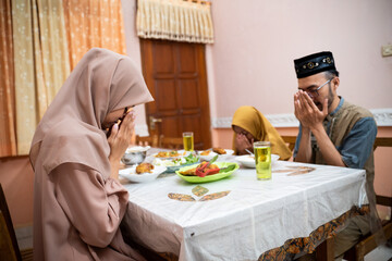 Fototapeta premium muslim family pray and thanking god for the food while breaking the fast on ramadan