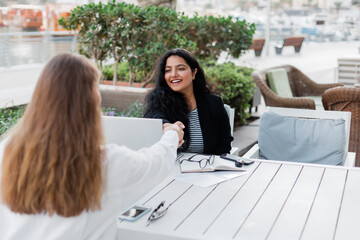 Two businesswomen make a deal during a meeting in a cafe. Business, work meeting, work outside the office.