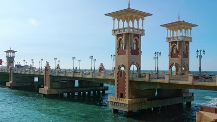 Stanley Bridge on waterfront promenade corniche in Alexandria. Cars driving over architectural construction in Mediterranean sea with beautiful towers, street lamps in Egyptian city
