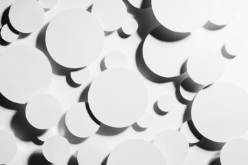 White paper circles different size as mess swarm random abstract  pattern in hard light with contrast black strict shadows, top view. Contemporary simple stable bright abstract background.