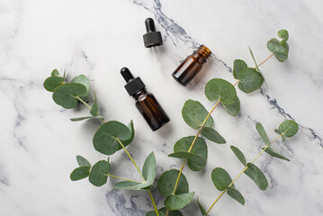 No plastic concept. Top view photo of glass dropper bottles and eucalyptus branches on white marble background