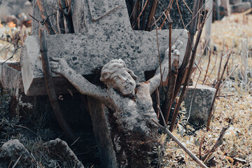 Toppled stone crucifix, broken gravestone at abandoned ancient cemetery Mystery halloween concept,...