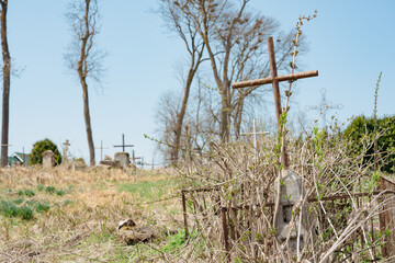 Unknown burial with weathered metal cross at abandoned cemetery against blue sly. Old churchyard....