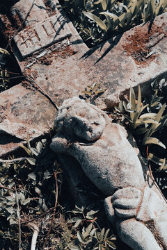 Vertical image with stone crucifix on the ground. Abandoned ancient cemetery with broken tombstone. Mystery halloween concept, old churchyard
