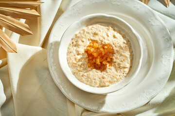 Oatmeal with caramelized apples in a white plate. Hard light. Selective focus.