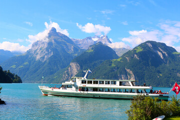 Ferry on the green water of Lake Lucerne surrounded by the Alps mountains (Sisikon, Switzerland) 