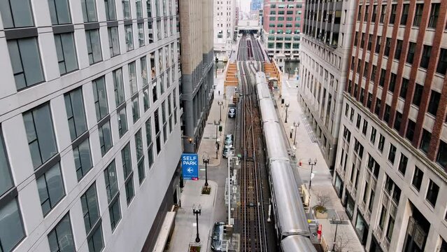 Aerial view following a train driving in middle of buildings and over the Wells Street bridge in downtown Chicago, USA