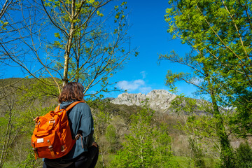 Naklejka premium A young woman with a backpack looking at the mountains and the Sella river between El Tornin a la Olla de San Vicente, near Cangas de Onis. Asturias. Spain
