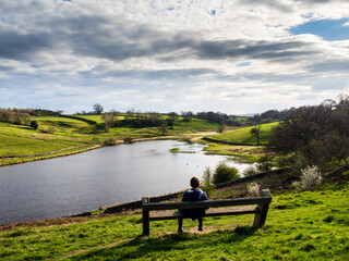 John O' Gaunt reservoir in Nidderdale in Yorkshire. A beautiful Spring afternoon and the views are lovely. A person is sat on a bench enjoying the views