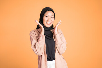suprised young muslim woman opening both palms while smiling at camera on isolated background
