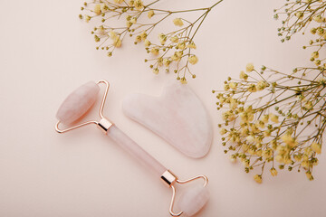 Self care and beauty theme. Face roller and gua sha massager with branch of yellow gypsophila. Top view
