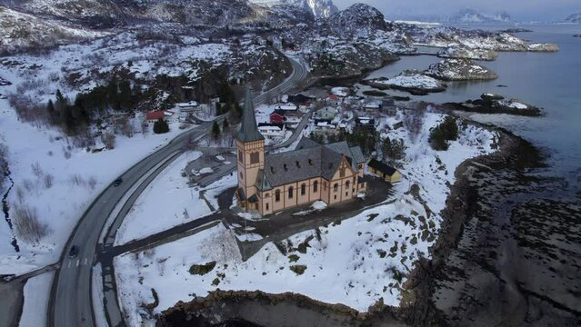 Magnificent aerial orbit of Kabelvag Church in winter with snow covered mountains in the background, Lofoten Cathedral.