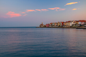 Picturesque view of coastline of Adriatic sea with colorful houses and lighthouse at sunrise, Piran, Slovenia