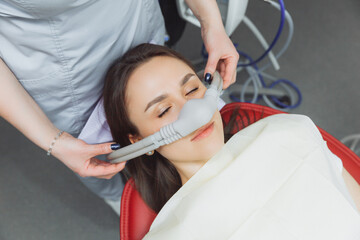 dentist puts inhalation sedative mask on his patient. - obrazy, fototapety, plakaty