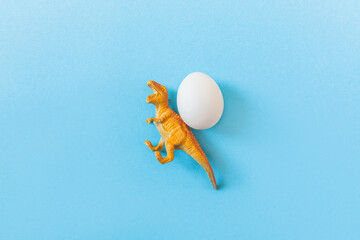 Easter egg hunt holiday composition, white eggs with dinosaur on light blue backgroind. Seasonal spring kids game concept. Flat lay, top view, place for text, banner