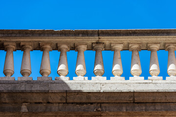Fototapeta na wymiar Close-up of a white marble balustrade in classical style against a clear blue sky and copy space. Brescia downtown, Lombardy, Italy, Europe. 