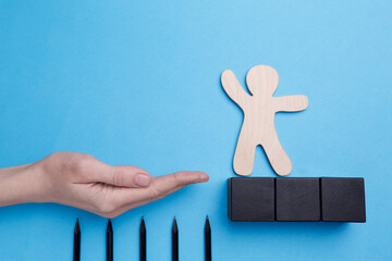 Woman holding hand to help human figure avoid trap with pencils as spikes on light blue background,...