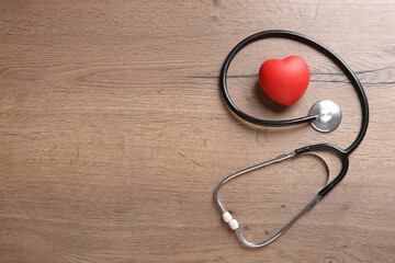 Stethoscope and red heart on wooden table, flat lay with space for text. Cardiology concept