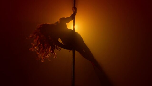 Seductive girl performing sexy dance on club pylon. Woman practicing poledance 