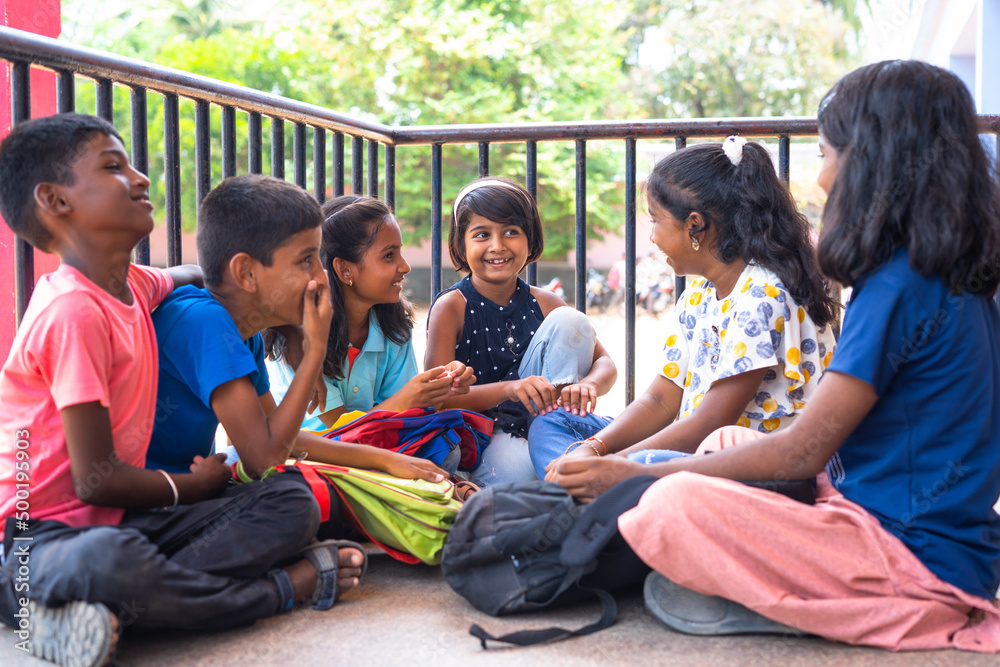 Wall mural group of teenger children talking with friends while sitting at school campus during break time - co