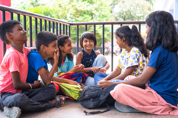 group of teenger children talking with friends while sitting at school campus during break time - concept of communication, conversation and childhood things.