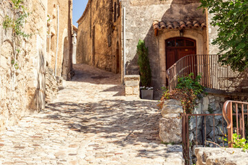 Fototapeta na wymiar Narrow cobblestone streets limestone medieval buildings of ancient notoriously famous Lacoste town at summer. Vaucluse, France