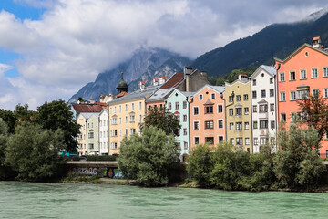 Fototapeta na wymiar Innsbruck from the Inn River with Colorful Buildings and Mountains during Cloudy Summer Day. Beautiful Architecture of Alpine City in Tyrol.