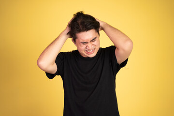 Stressed asian young young man holding head on isolated background