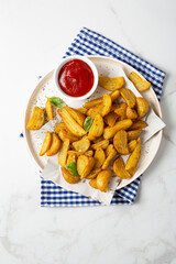 Top view of potatoes wedges and red sauce on plate