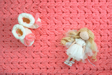 Handmade baby white booties for girls on a knitted pink plaid. A fashionable newborn. Flat position, top view. Place for text