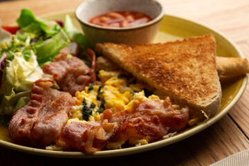 Poached eggs with vegetable, ham, tomatoes, red beans and sourdough toast isolated on wood background. Homemade food. Tasty breakfast.