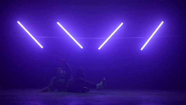 Guy making breakdance tricks on nightclub dance floor. B-boy performing hiphop.