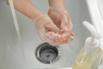Fototapeta premium Woman washing hands with liquid soap, closeup