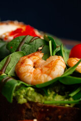 Buckwheat bread toasts with a poached egg, a sliced avocado, a shrimps, tomatoes and lettuce. Dietary menu. Flat lay.