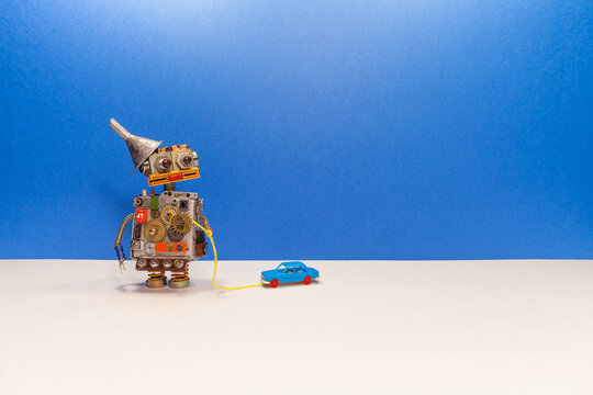 Robot game. Mechanical robot pulls a miniature plastic car automobile on a rope